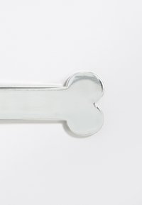 Oggetto argenteo a forma di osso con superficie lucida, caratterizzato da estremità arrotondate e texture liscia. Adatto per vari usi decorativi.