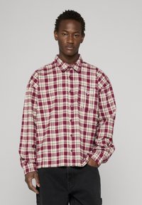 Rood- en beige geruit overhemd met lange mouwen, spitse kraag, knoopsluiting aan de voorkant en een borstzak aan de linkerkant. Gemaakt van katoenstof met een zachte textuur.