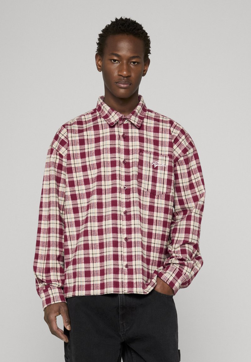 Rood- en beige geruit overhemd met lange mouwen, spitse kraag, knoopsluiting aan de voorkant en een borstzak aan de linkerkant. Gemaakt van katoenstof met een zachte textuur.
