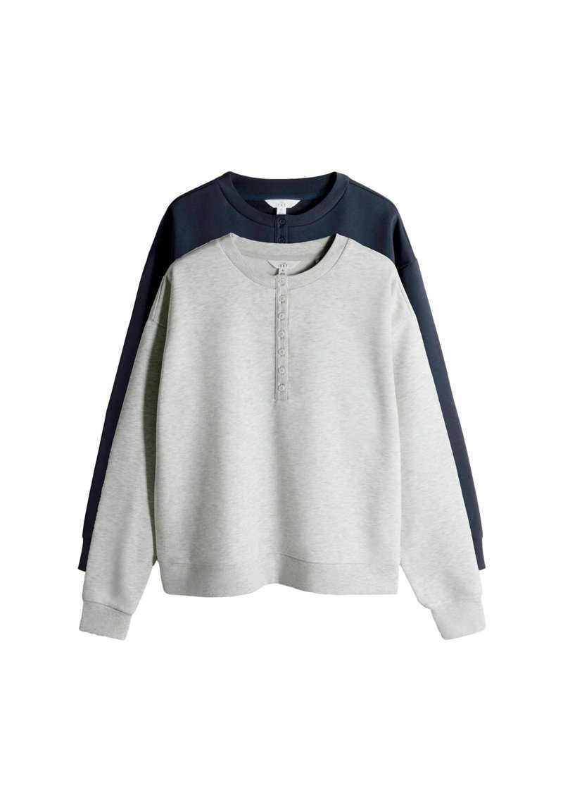 Lichtgrijze sweatshirt met donkerblauwe accenten, knopen bij de halslijn, geribbelde manchetten en zoom; oversized pasvorm en zachte textuur.