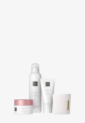 Fire Rituals Sakura-produkter: bodyscrub, skummende brusegel, bodycreme og en ribbet hvid lysestage med gyldent mærke.