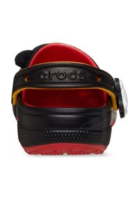 Zwarte Crocs met een rode binnenkant, voorzien van een gele band en een karakterthema-accent aan de zijkant. Gevoerde zwarte buitenzool voor grip.