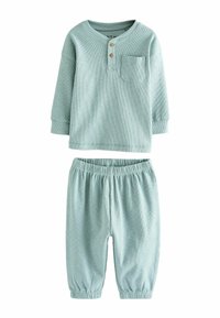Conjunto de dos piezas de tejido acanalado en verde claro que incluye una blusa de manga larga con un bolsillo y dos botones de madera, y pantalones con cinturilla elástica.