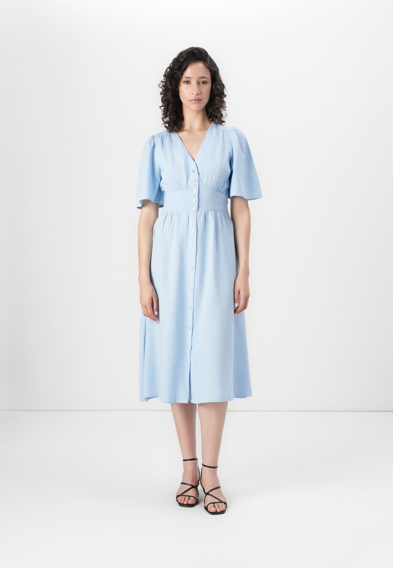 Rochie midi de culoare bleu deschis, cu decolteu în V, mâneci scurte tip puff și nasturi frontal. Material neted, cu o croială lejeră și talie elastică.