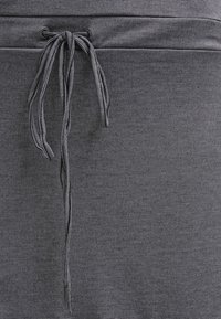 Zbliżenie na szary materiał z troczkiem w czarno-białe paski, teksturowana powierzchnia i subtelny wzór.