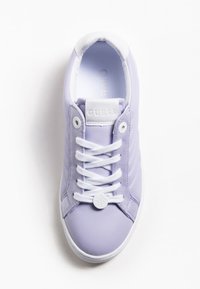 Sneaker viola con pannelli lisci e testurizzati, lacci bianchi e una linguetta con il marchio. Presenta un accento rotondo nell'area dei lacci.