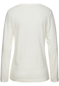 Long-sleeve top in cream, made of smooth fabric. Features a classic round neckline and a straight cut with a slightly rounded hem.