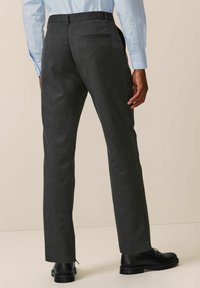 Pantalons gris ajustés avec une texture lisse, coupe droite et une poche arrière simple. Associés à des bottes noires à lacets.