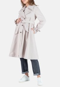 Licht begeren trenchcoat met een brede kraag, dubbelknops ontwerp en een ceintuur in de taille. Heeft lange mouwen met geplooide manchetten en zijzakken.