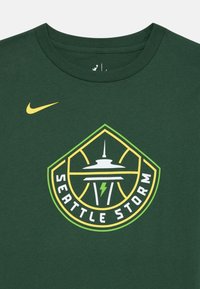 Zeleni pamučni majicu s logotipom Seattle Storm, kružnim dizajnom s žutim munjama i Svemirskom iglom, obrubljenim u žutoj i zelenoj boji.