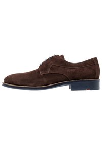 Chaussure habillée en daim marron avec un bout rond, des coutures minimalistes, des accents de lacets bleus et une semelle noire. Talon plat avec un détail de bord contrastant.