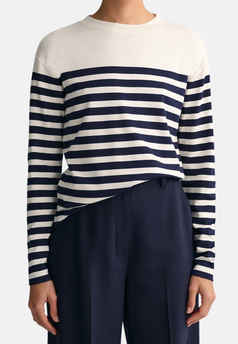 Langärmliges Oberteil mit horizontalen Streifen in Marineblau und crème, runder Ausschnitt, lässige Passform, aus weichem Baumwollstoff mit sichtbaren Nähten.