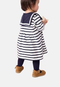 Robe rayée avec col bleu marine, en tissu de coton doux, design en forme de cloche, assortie à des collants bleu marine et des chaussures en suède marron avec boucle.