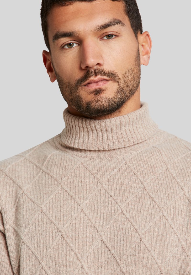 Maglione a collo alto a maglia color beige chiaro con motivo a rombi, colletto a coste e texture morbida. Nota: il viso della modella è parzialmente visibile.