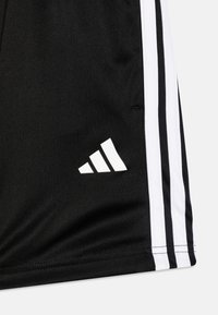 Czarne sportowe spodenki z gładkiego, lekkiego materiału, z białymi paskami po bokach i białym logo w dolnym lewym rogu.