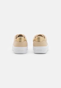Beige leather sneakers with a white rubber sole. Smooth texture with a gold accent on the heel and embossed logo on the back.