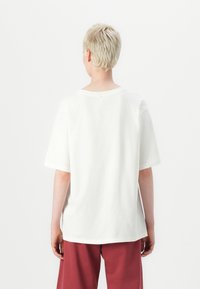 T-shirt en coton blanc à manches courtes, à col rond et à coupe décontractée. Texture lisse ; pas de motifs ou d'accents visibles.