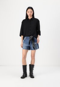 Black button-up shirt with three-quarter sleeves, denim shorts featuring a tie, and knee-high black boots with multiple buckles.