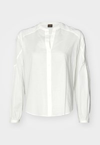 White button-up shirt made of light fabric, featuring a collar, long sleeves, and a relaxed fit. Subtle stitching detail along shoulder seams.