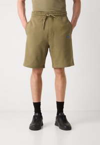 Olivengrønne sweatshorts med elastisk talje og snøre, med to sidelommer og et lille blåt logo på fronten.