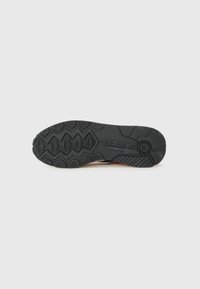 Sort gummisål til sneaker med et struktureret mønster, der inkluderer hexagonale og zigzag former; har "adidas"-branding på siden.
