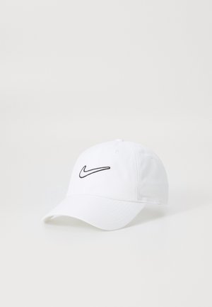 Biała czapka baseballowa z zakrzywionym daszkiem i czarnym logo Nike Swoosh wyszytym z przodu.