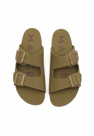 Sandali verde oliva con due larghe cinghie e fibbie beige regolabili. Suole interne testurizzate con la scritta "MAE" stampata in marrone. Forma piatta e arrotondata.