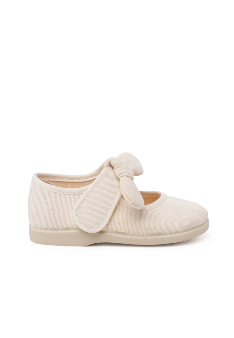 Beige Textilschuh mit abgerundeter Zehe, elastischem Riemen mit Schleifendetail und einer weichen, flachen Sohle. Das Obermaterial hat eine glatte, strukturierte Oberfläche.