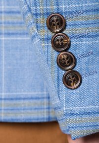Jasnoniebieska materiałowa marynarka w kratkę z wyraźnymi brązowymi guzikami, posiadająca dwa otwory i subtelny połysk. Widoczne szczegółowe przeszycia.