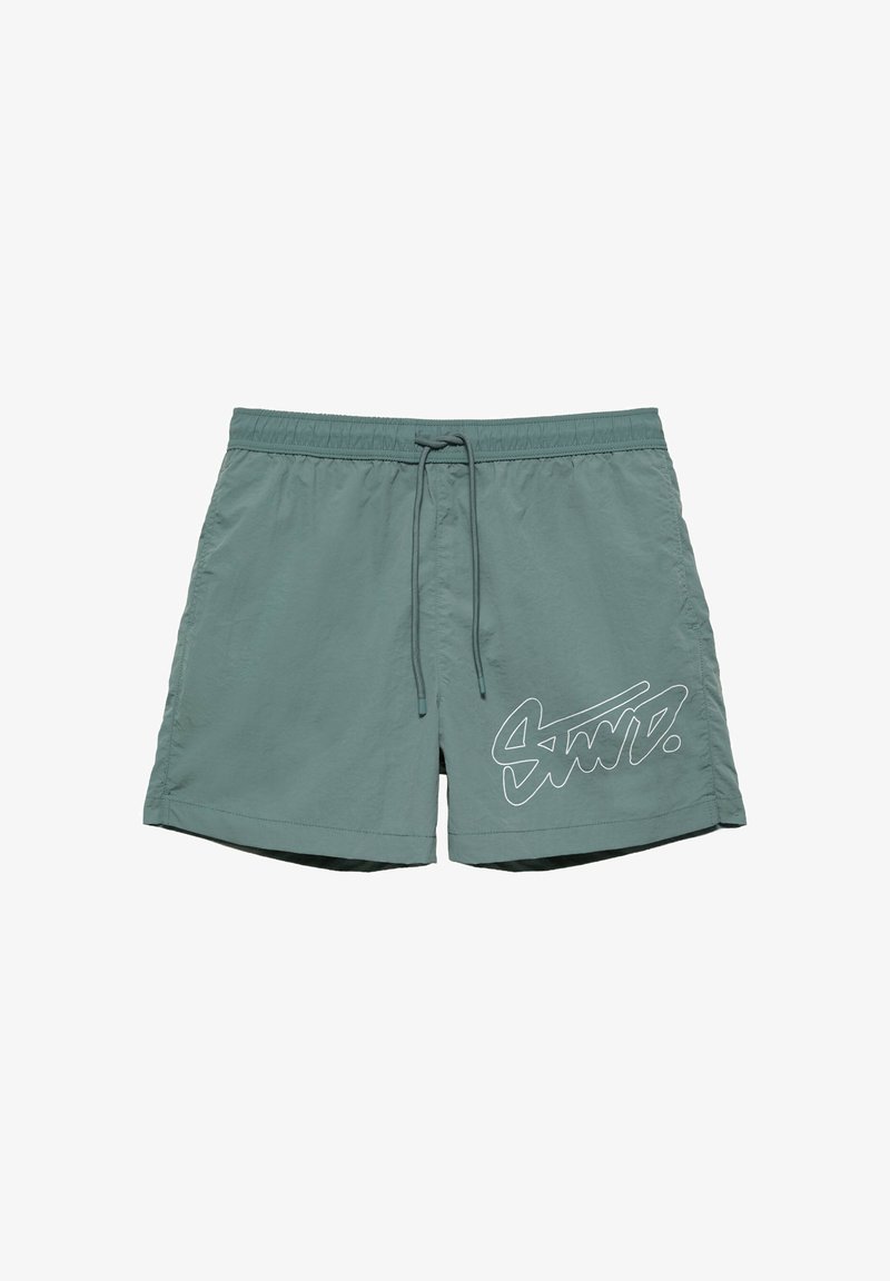 Short de bain vert avec taille élastique, cordon de serrage et logo blanc stylisé sur la partie inférieure de la jambe gauche.