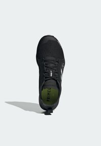 Scarpa atletica nera con tomaia in mesh testurizzato, lacci piatti, suola in gomma e soletta verde con testo "PRIMEG". Design minimalista senza loghi visibili.