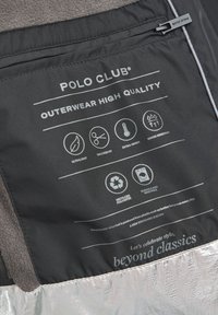 Svart jacktyg med grått fleecefoder. Innehåller logotyper, skötselinstruktioner och symboler som indikerar lätt, varmt och vattentåligt design. Silverfärgad nederkant.