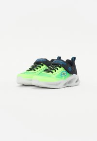 Sneaker verde neon con accenti neri, parte superiore in rete testurizzata, chiusura con lacci e suola semi-trasparente con ammortizzazione d'aria visibile.