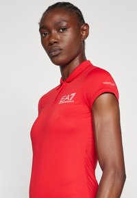 Rode polo shirt van een textuurstof, slim fit, met een kraag en korte mouwen. Logo op de borst en "VENTUS" op de mouw.