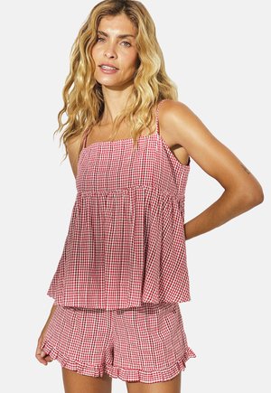 Červený a biely kostkovaný crop top s elastickým živôtikom; spárovaný s rovnakými šortkami so volánovým lemom. Mäkkučký materiál, voľný strih.