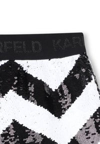 Paillettenrok met een chevronpatroon in zwart, wit en grijstinten. Heeft een zwarte tailleband met de tekst "KARLFELD" in glitters.