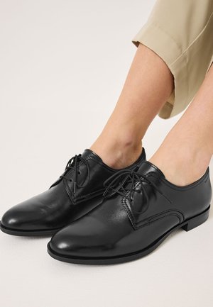 Schwarze Leder-Schnürschuhe mit abgerundeter Zehenpartie, glatter Textur und niedrigem Absatz. Verfügt über dekorative Nähte und schlanke Schnürsenkel.