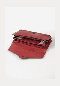 Red leather clutch wallet with a zippered compartment, multiple card slots, and a snap closure. Smooth texture, structured shape.