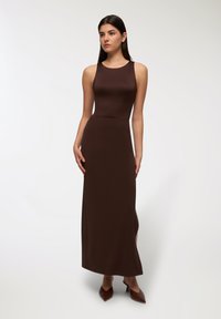 Brązowa, dopasowana sukienka maxi z dekoltem na ramiączkach, wykonana z gładkiej, elastycznej tkaniny, z delikatnym rozcięciem po boku i minimalną ilością szwów.