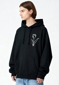 Sweat à capuche noir avec un design de tulipe blanche sur la poitrine, doté d'une poche avant et d'une capuche à cordon. Matière en mélange de coton, coupe décontractée.