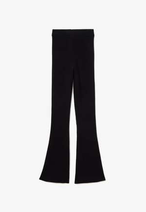 Pantalones de canalé negros acampanados con una cintura alta y una tela suave y texturizada. Las piernas se ensanchan drásticamente desde la rodilla hasta el dobladillo.