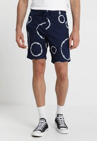 Námorně modré šortky s bílými vzory kroužků ve stylu tie-dye. Vyrobené z prodyšné tkaniny, s elastickým pasem a stahovací šňůrkou.