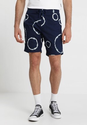 Shorts bleu marine avec des motifs de cercles en tie-dye blanc. Fabriqués en tissu respirant, avec une taille élastique et un cordon de serrage.