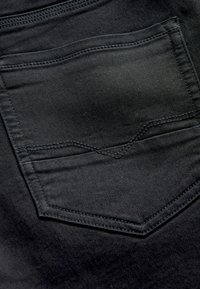 Čierna deniminová tkanina so šitým zadným vreckom s vzorom chevron. Hladká textúra, minimalistický dizajn a jemný lesk.