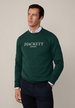 Grøn sweatshirt lavet af stof, med rund hals og lange ærmer, prydet med "HACKETT LONDON" trykt i hvidt på forsiden.