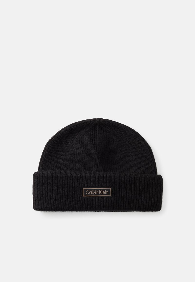 Must mustrüüga must kootud beanie, millel on volditud serv ja ees pronksist ristküliku kujuline logo silt.