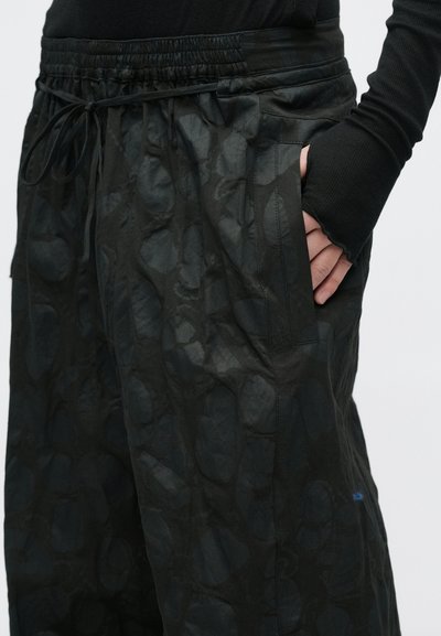 Μαύρο ελαφρύ παντελόνι με υφή, ελαστική μέση και κορδόνι· διαθέτει πλαϊνές τσέπες και άνετη εφαρμογή.