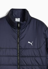Mørkeblå polstret jakke med høj krave, sort lynlås foran og hvid Puma-logo på venstre bryst.