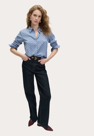 Lys blå button-up skjorte med mørke prikker, parret med høj talje mørke denim jeans og bordeaux spidse sko.