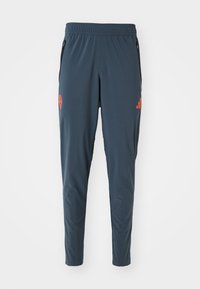Mørkeblå atletiske bukser med tætsiddende pasform, elastisk linning og røde logo accenter. Har lynlåslommer på siden til opbevaring.